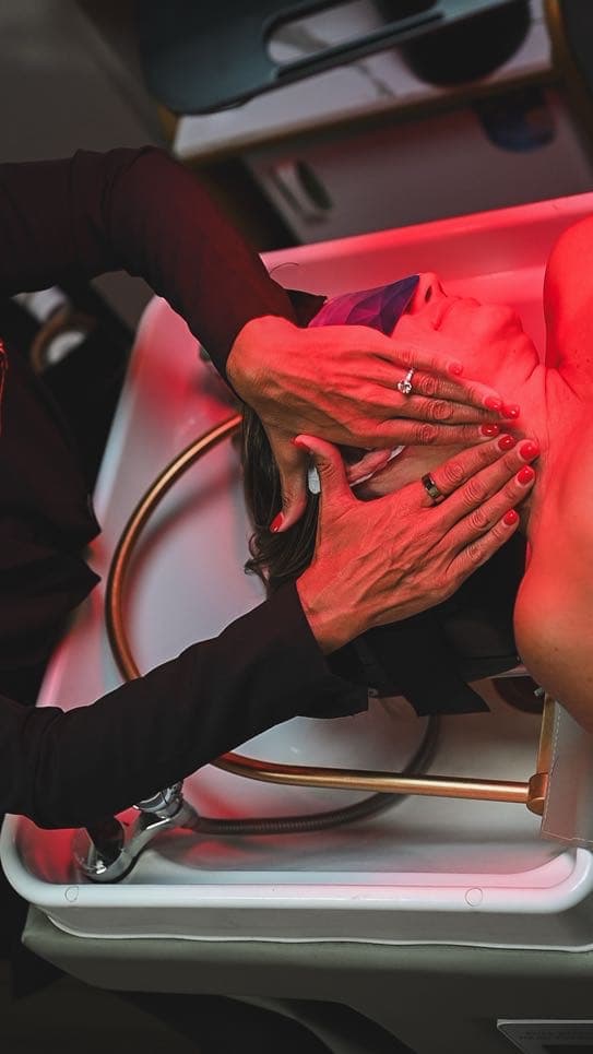 A specialist’s hands working through a slow scalp massage at the basin