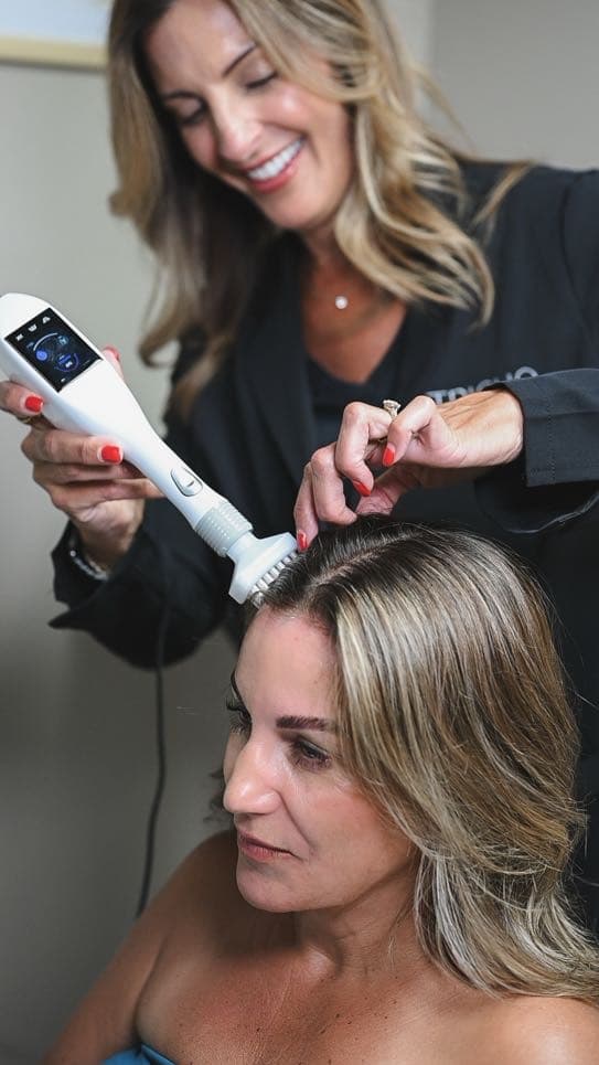 A jet plasma wand being worked along a guest’s part line at Serenity Scalp Spa