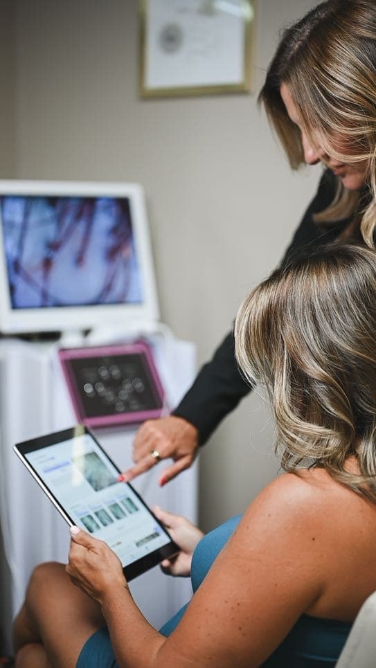 A guest reviewing her magnified scalp scan on a tablet during a consultation